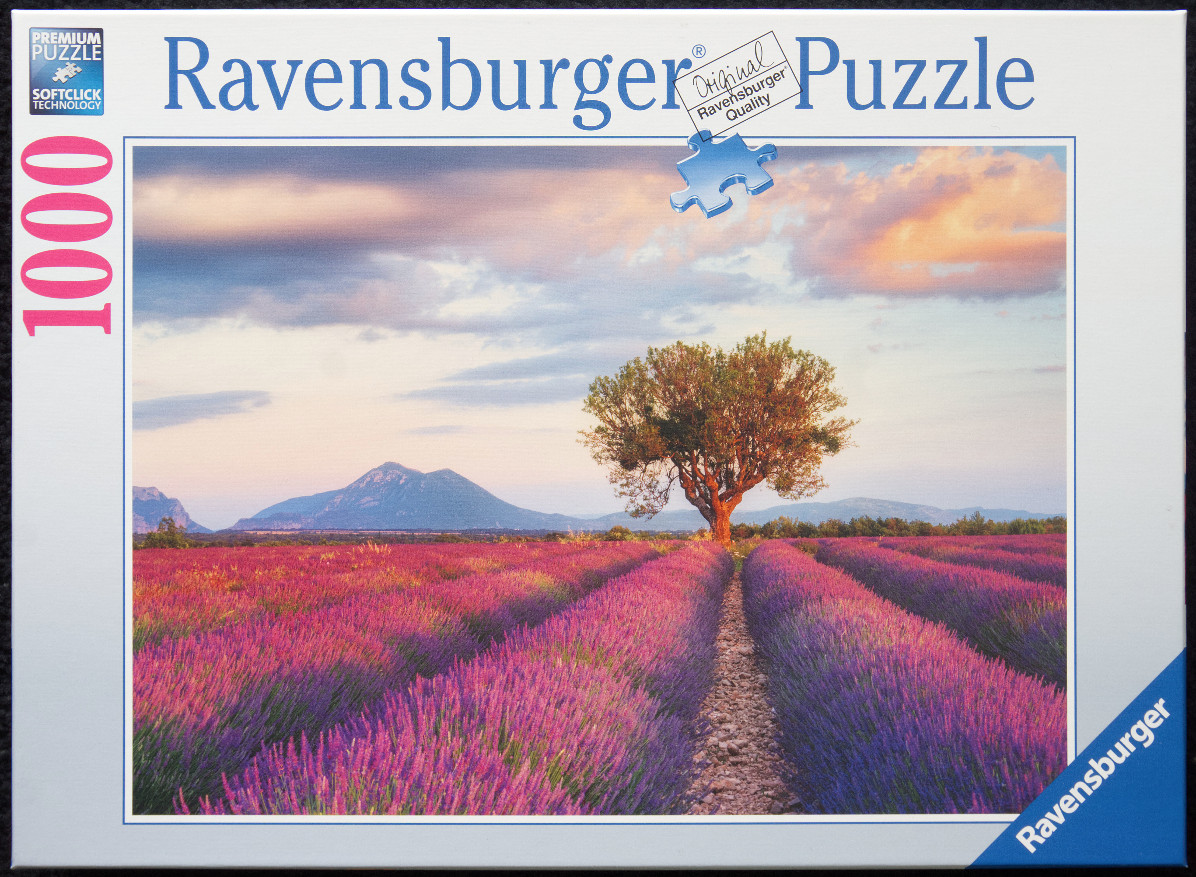 A scenic photograph of a blooming lavender field at sunset with a solitary tree and distant mountains.