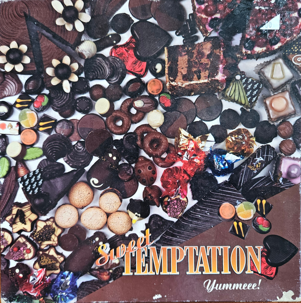 A dense, overhead collage of various chocolate candies, cookies, and fruit-topped confections.