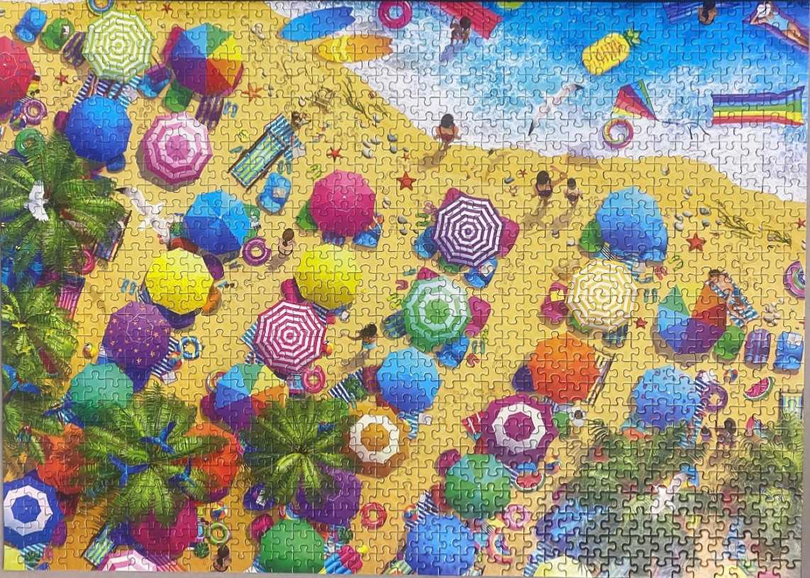 Aerial view of a crowded, colorful beach scene with many umbrellas and palm trees.