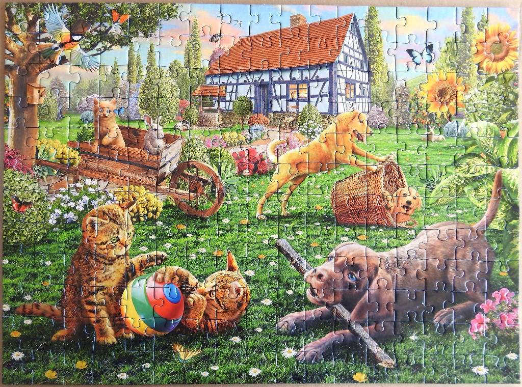 A sunny garden scene with a timber-framed house, various playful puppies, kittens, and a rabbit.