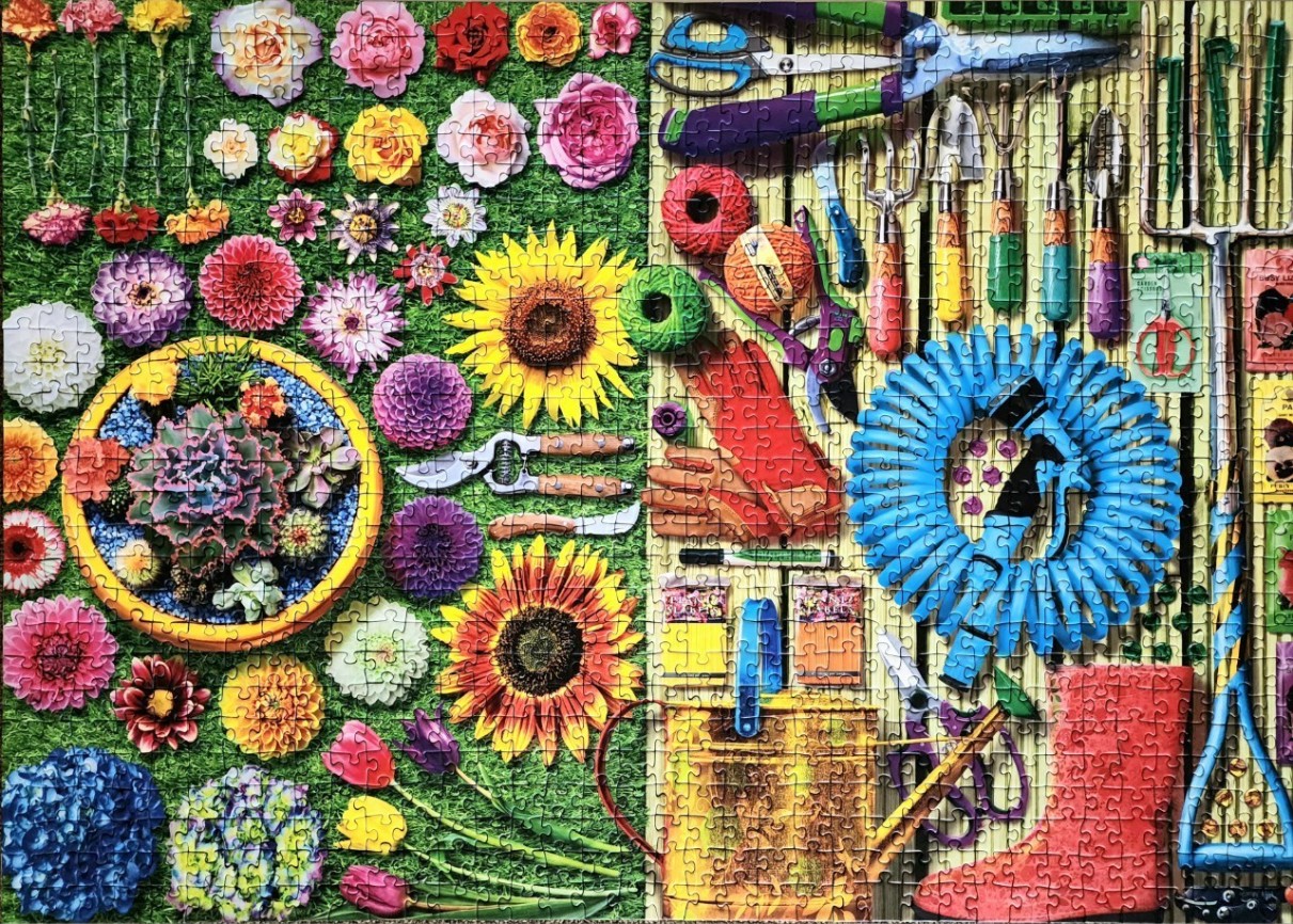 A flat-lay collection of gardening tools, seeds, and vibrant flowers against a backdrop of lawn and wooden slats.