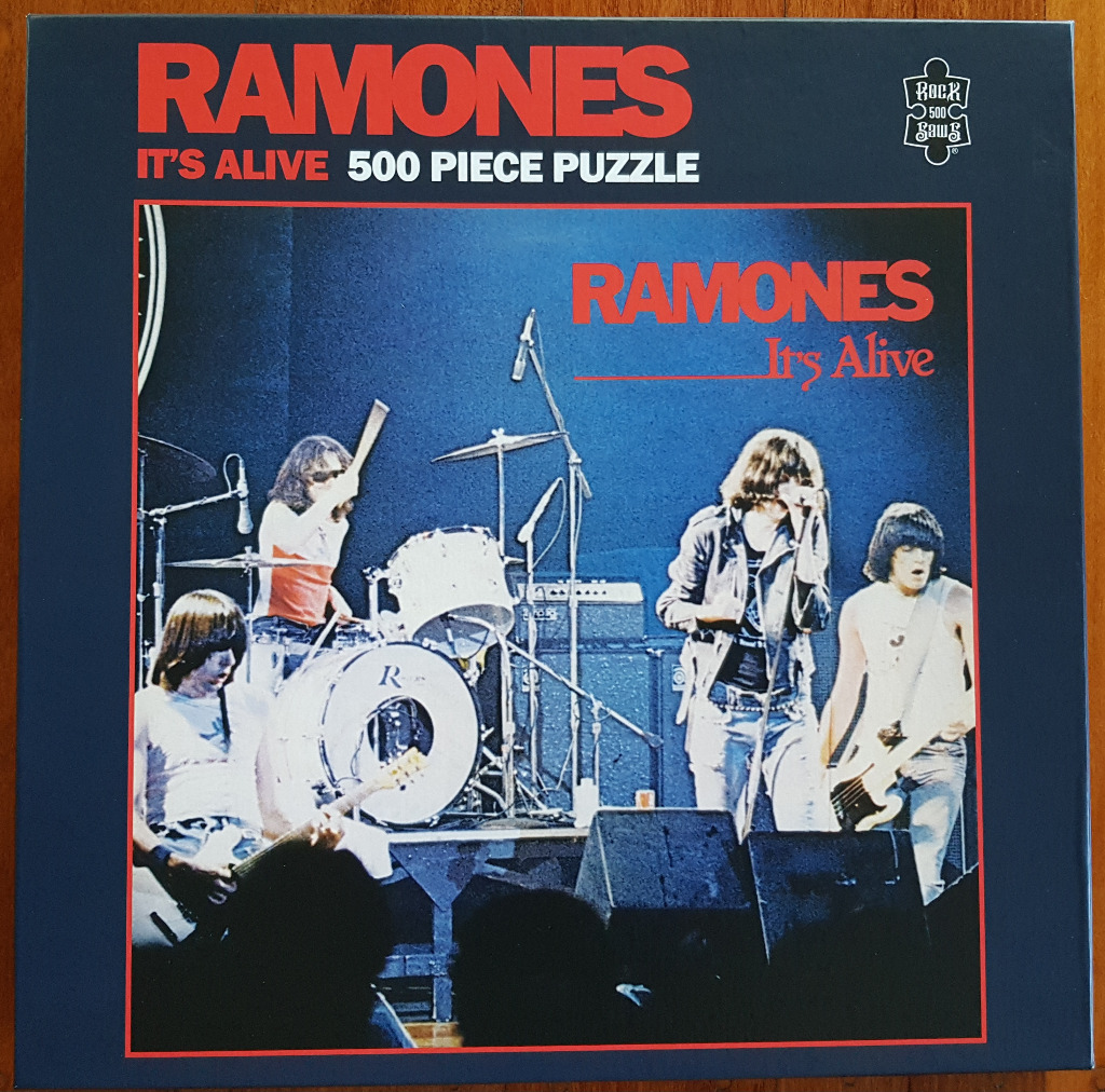 A live concert photograph of the band Ramones performing on stage with red text overlay.
