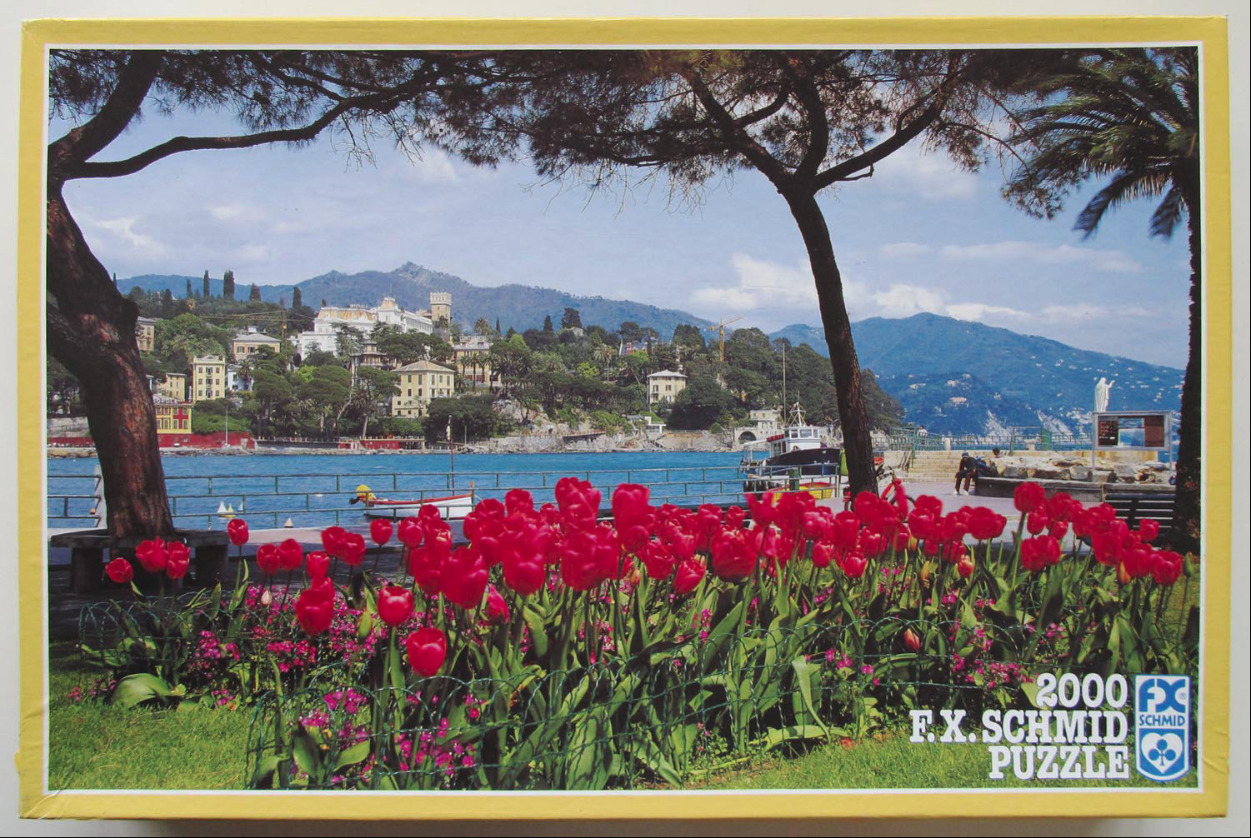 A vibrant foreground of red tulips framed by tree trunks, overlooking a Mediterranean bay with coastal villas and hills.