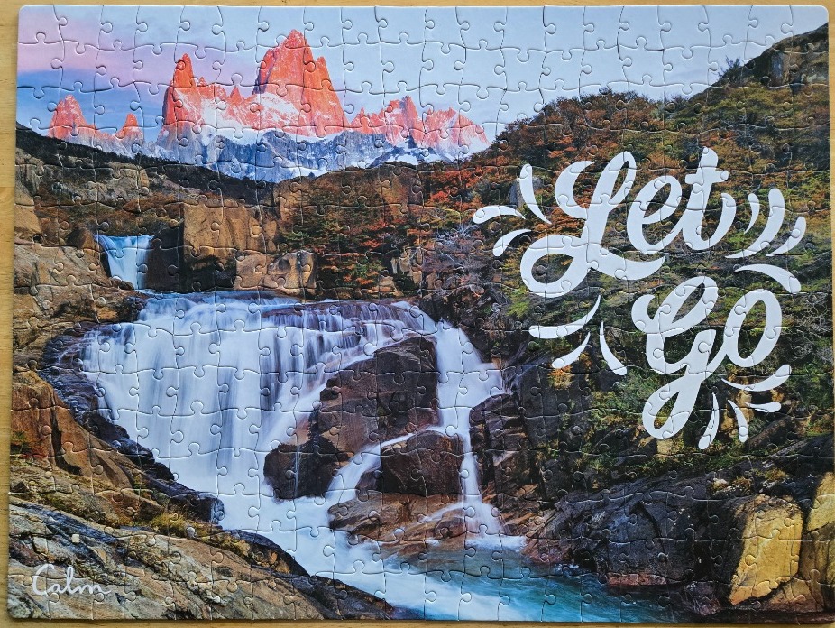 A scenic mountain waterfall landscape with the white calligraphic text Let Go overlaid on the right side.