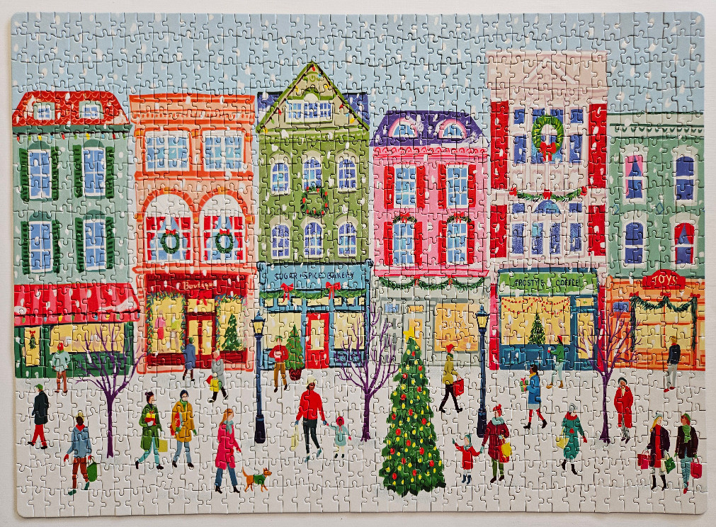 A whimsical illustration of a snowy town street lined with colorful shops and holiday shoppers.