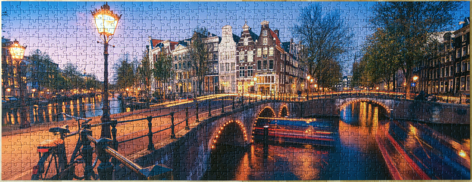 Evening view of an Amsterdam canal with illuminated historic houses and bridges