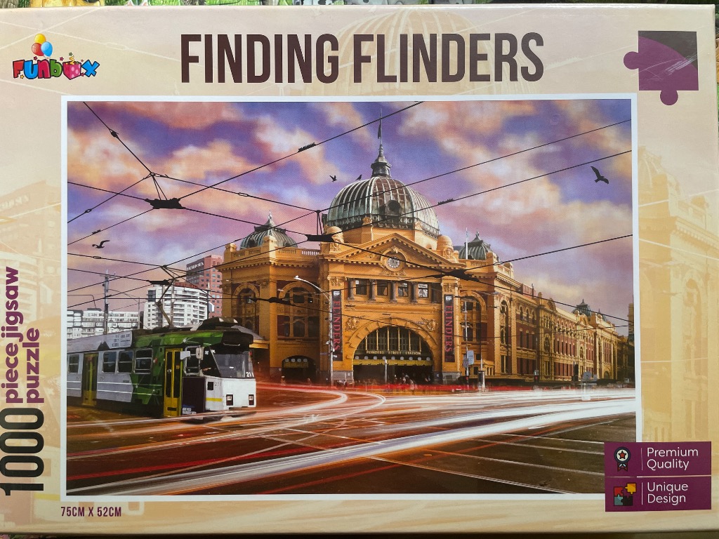 Flinders Street Station in Melbourne with a green and white tram in the foreground at sunset.