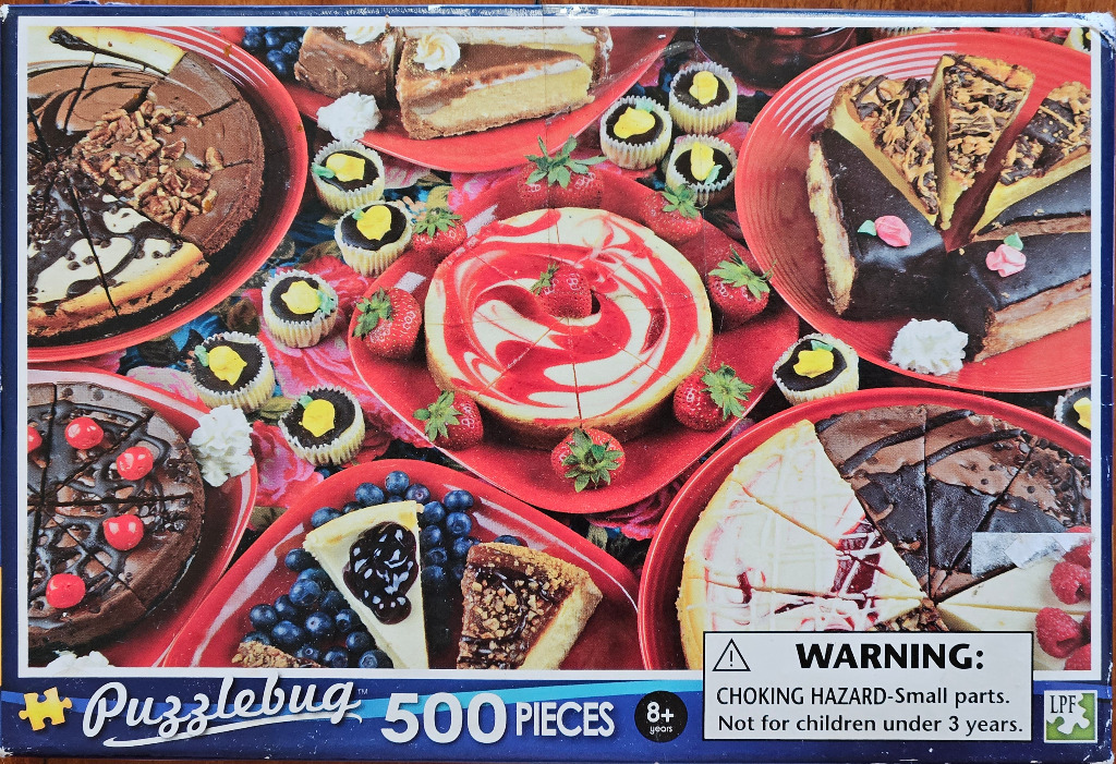A top-down view of several assorted cheesecake slices, whole cakes, and mini tarts arranged on red plates.
