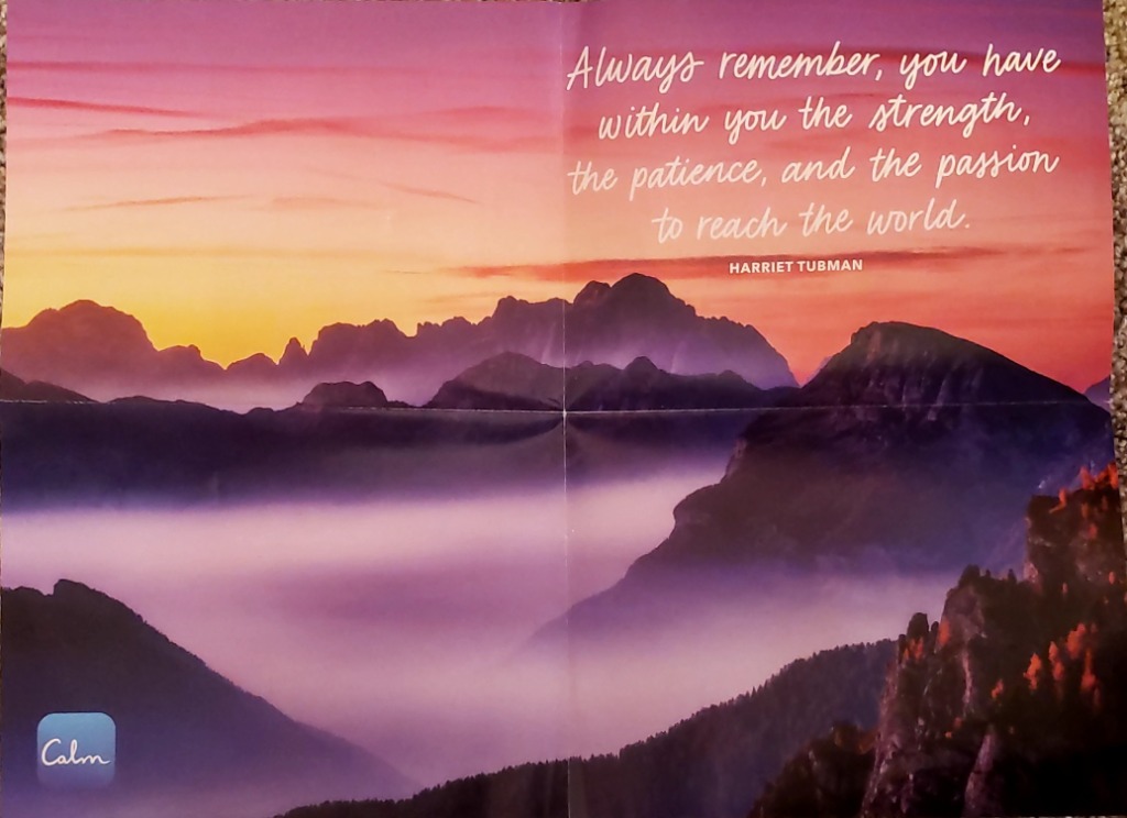 Mountains shrouded in mist under a pink and orange sunrise with an inspirational quote.