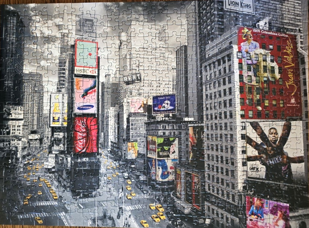 A black and white photograph of Times Square in New York City with pops of colour from the billboards.