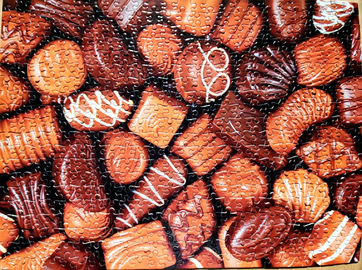 A close-up view of an assortment of various chocolate candies, featuring different shapes, textures, and drizzled designs.