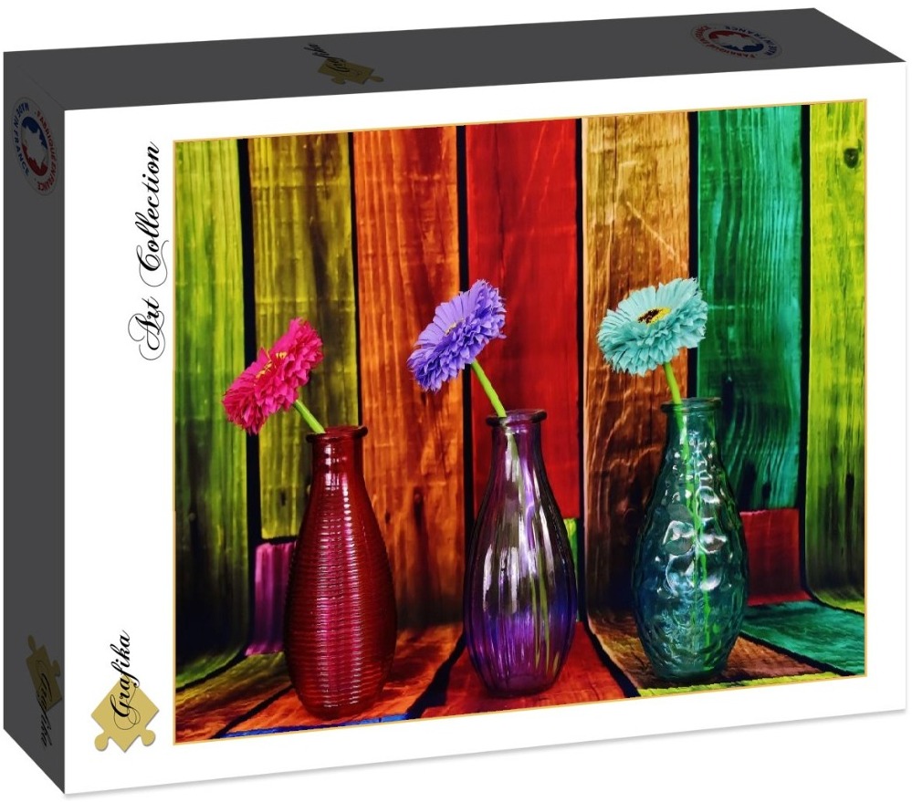 Three vibrant flowers in matching glass vases against a background of vertical, multicolored wooden planks.
