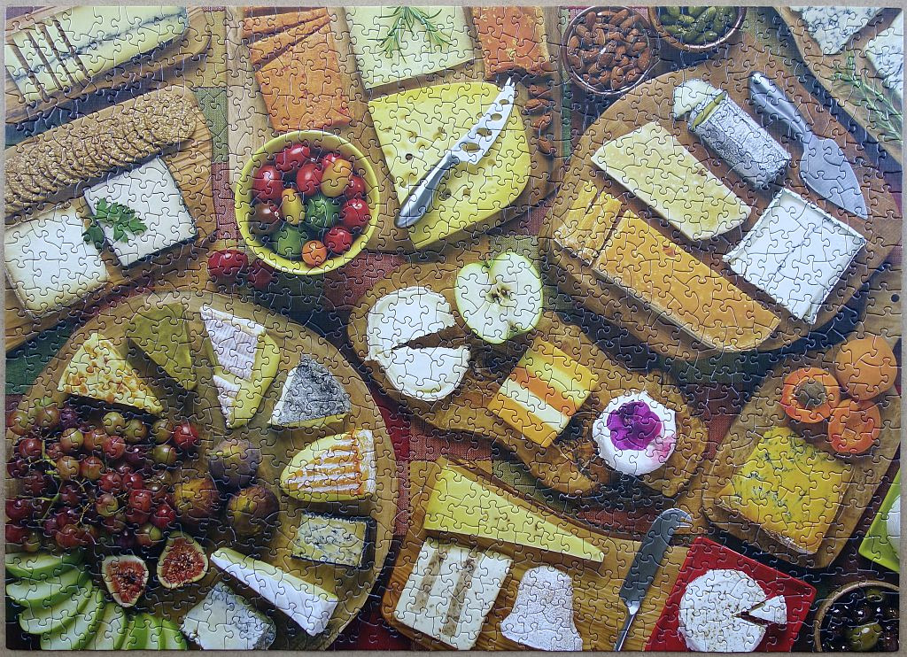 Overhead view of a generous charcuterie spread featuring various cheeses, fruits, and snacks.