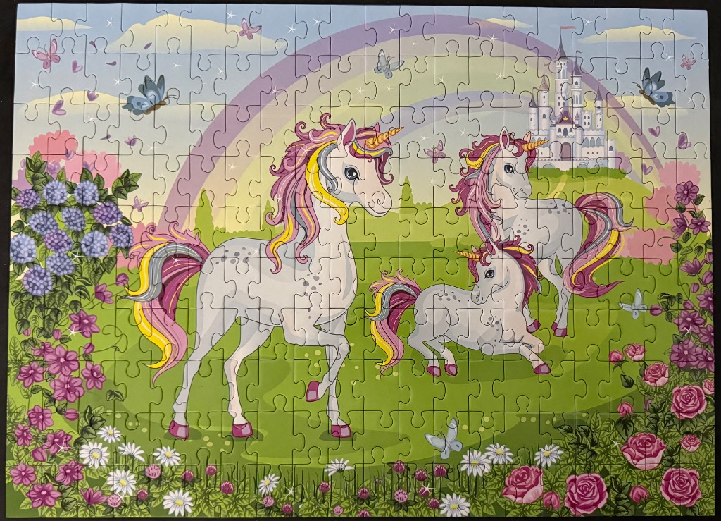 Three unicorns in a lush fantasy garden with a rainbow and castle