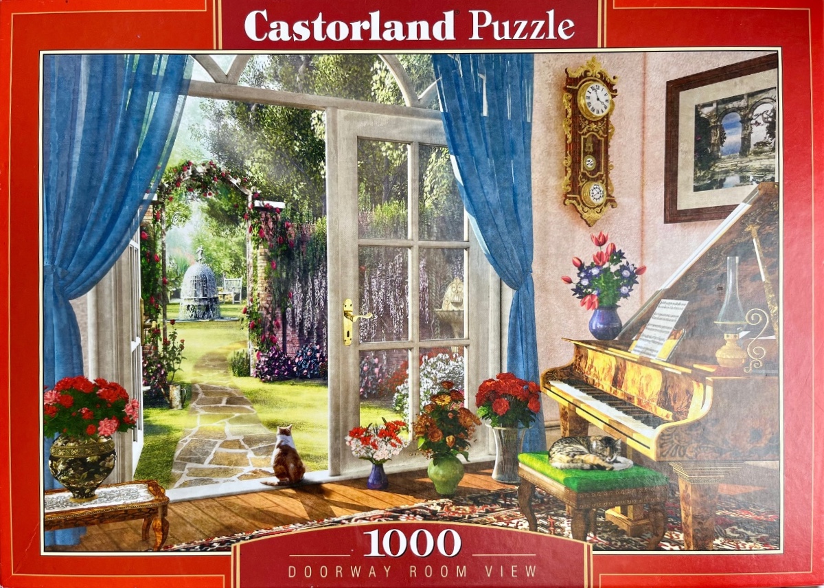 A sunny garden view from a sunroom with a piano and cats.