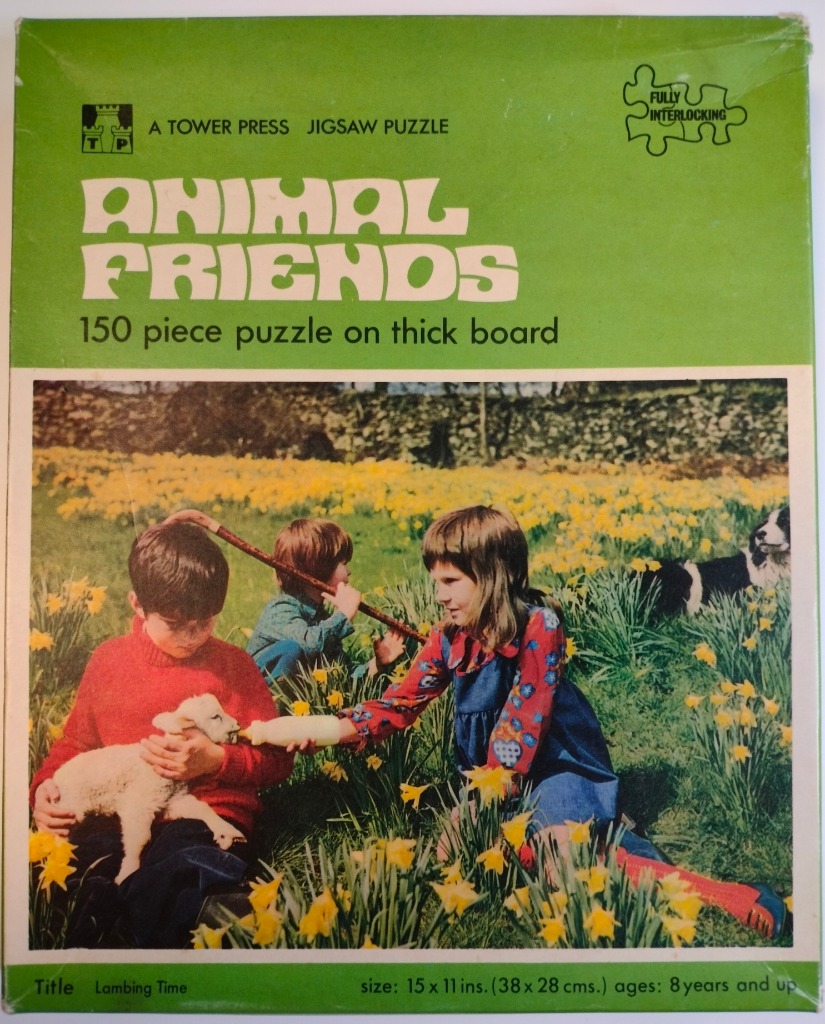 Two children sitting in a field of yellow daffodils, one bottle-feeding a white lamb while a dog looks on.
