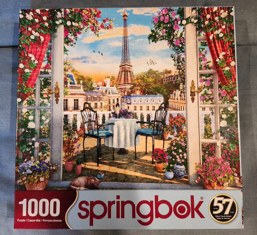 A balcony overlooking the Eiffel Tower in Paris, framed by red curtains and flowers.