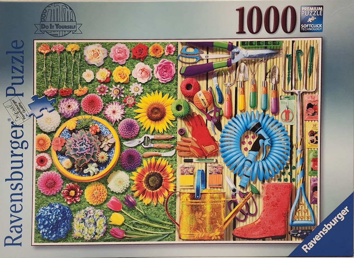 A collection of garden flowers and tools arranged on grass and wooden boards.