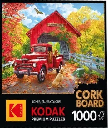 A red vintage truck parked in front of a covered wooden bridge surrounded by vibrant autumn trees and golden retriever dogs.