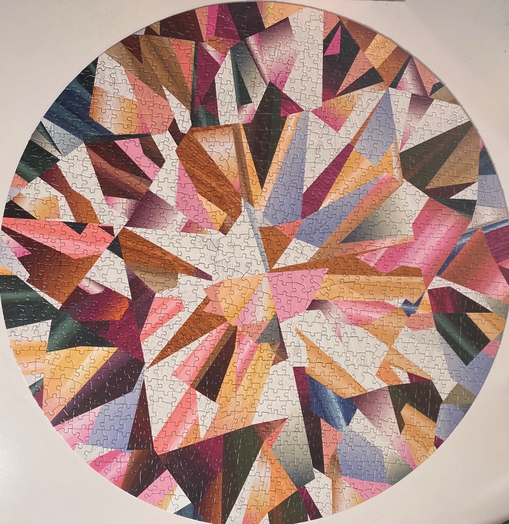 A round artistic representation of the facets of a diamond in pink, gold, and dark tones.