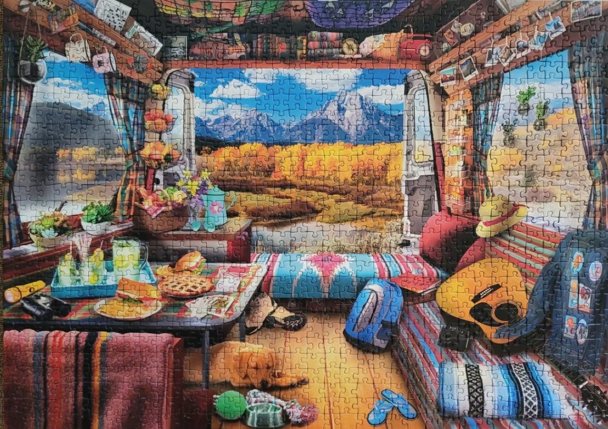 Interior view of a cozy campervan looking out at a vibrant autumn mountain landscape.