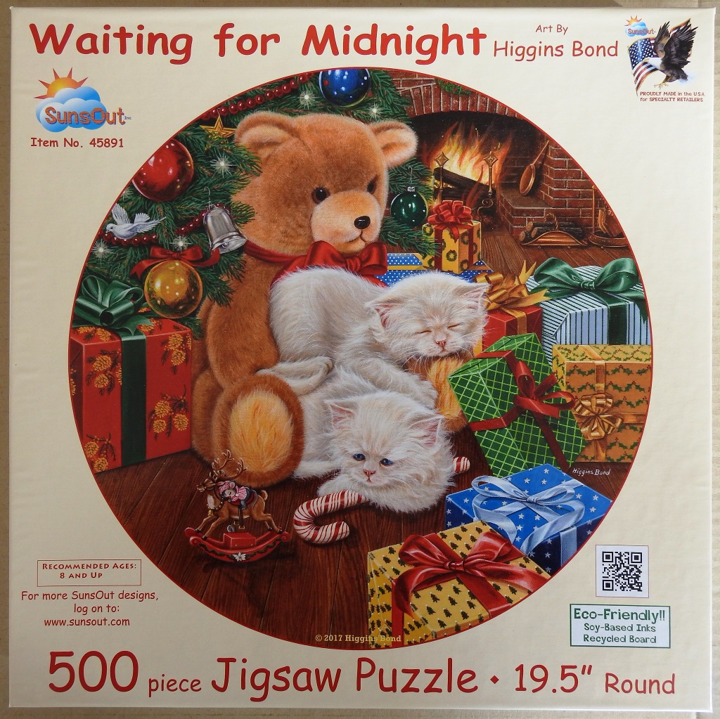 A teddy bear and two white kittens cuddling in front of a Christmas tree and fireplace.