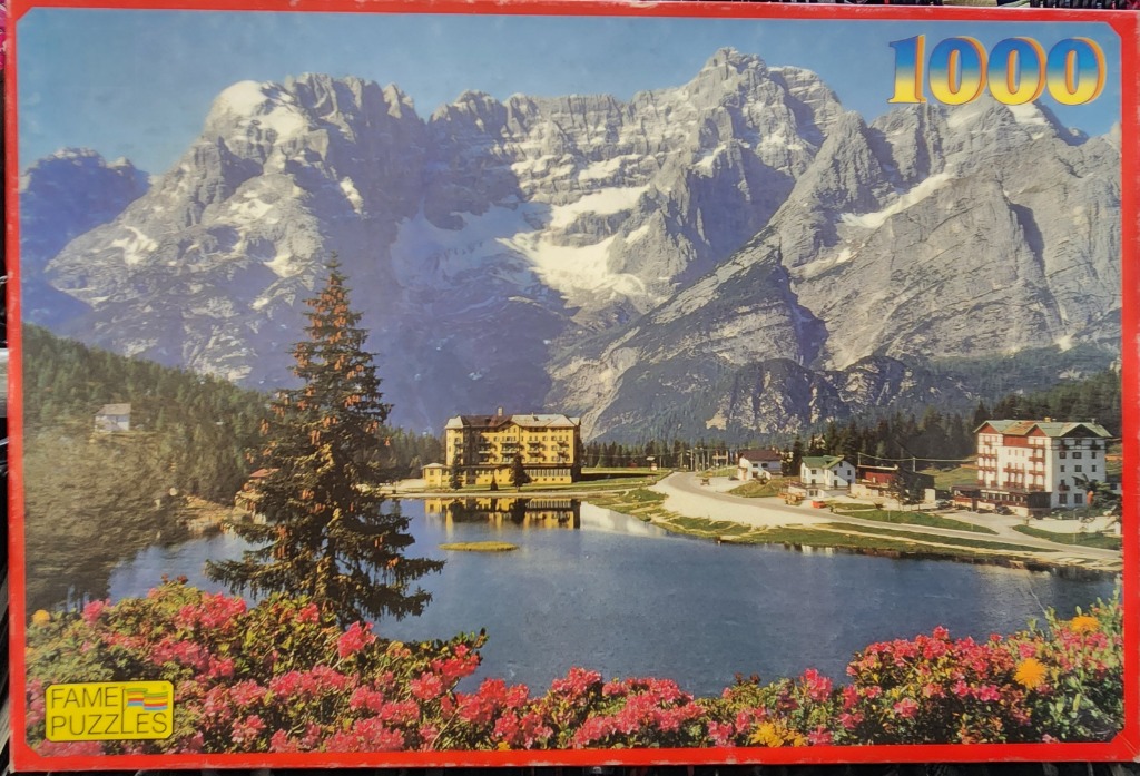 A tranquil alpine lake scene with grand mountains, a large hotel, and vibrant foreground flowers.