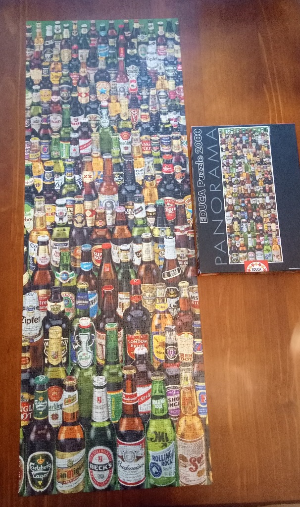 A vertical panoramic collection of many different beer bottles displayed in a dense grid.