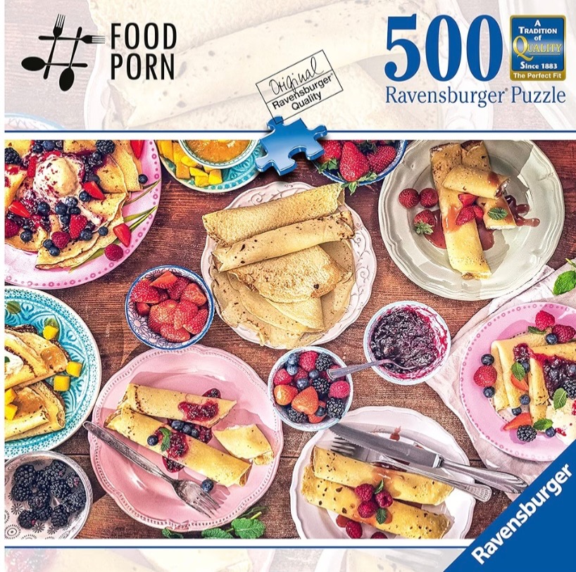 An overhead view of a rustic wooden table covered with plates of crepes, berries, and sauces.