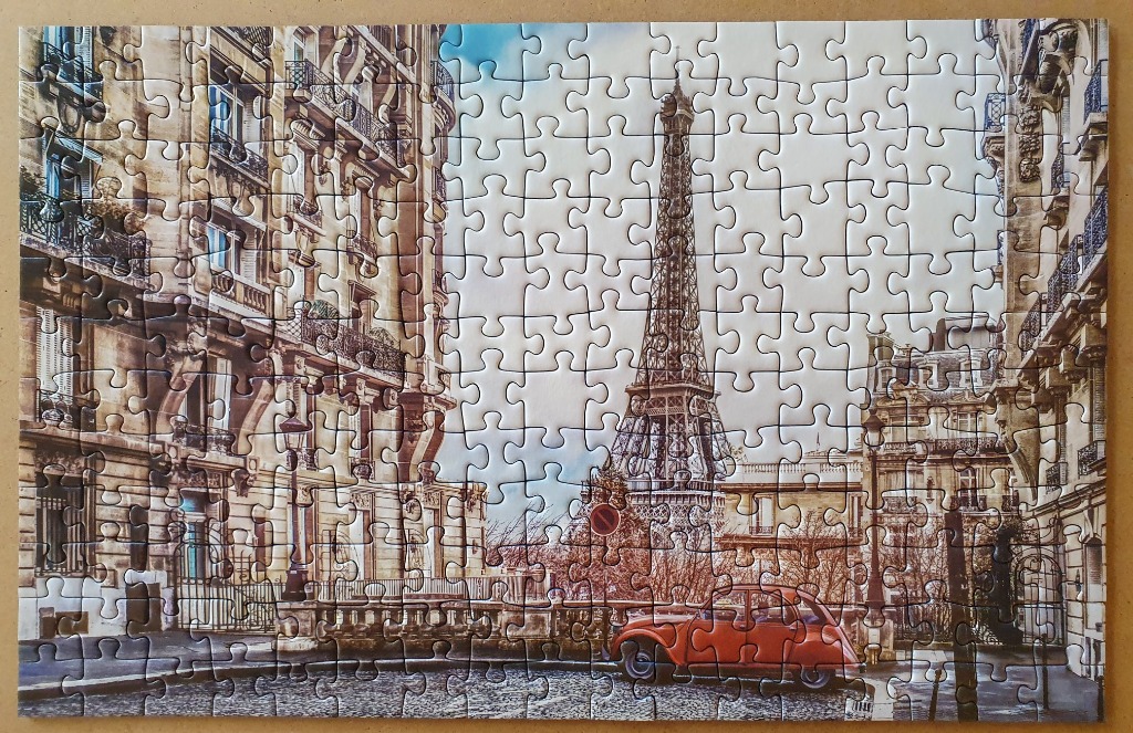 A Parisian street scene featuring the Eiffel Tower framed by classical Haussmann-style buildings and a vintage red car.