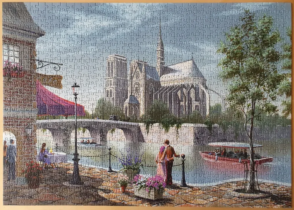 A painting of Notre-Dame Cathedral viewed from a Parisian riverside scene with a cafe and boat.