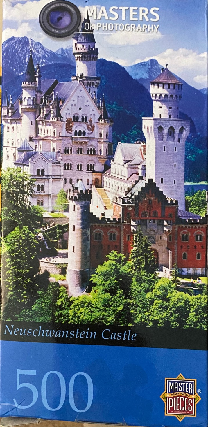 A photograph of Neuschwanstein Castle nestled in the Bavarian Alps under a blue sky.
