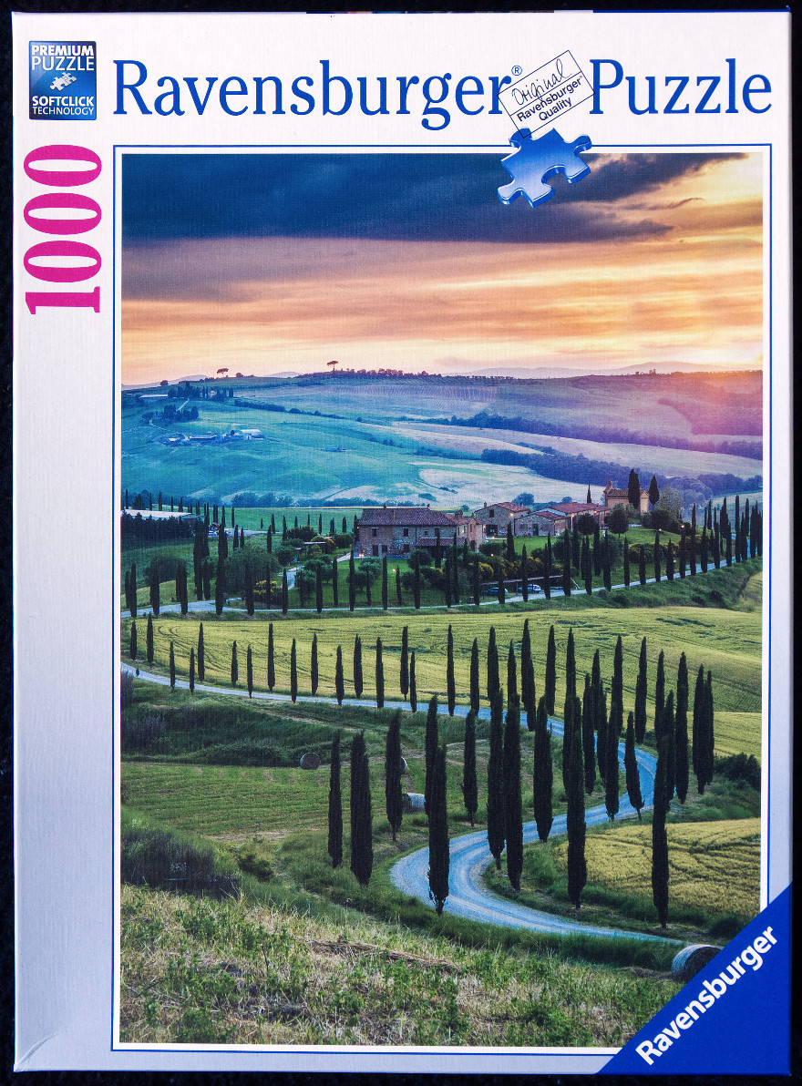 A Tuscan landscape featuring a winding road lined with cypress trees leading to a villa at sunset.