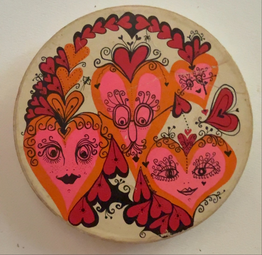 Stylized illustration of three heart-shaped faces with whimsical details in shades of pink, orange, and red.