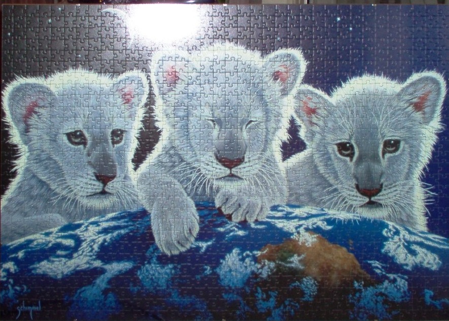 Three white lion cubs resting their paws on top of planet Earth against a dark space background.