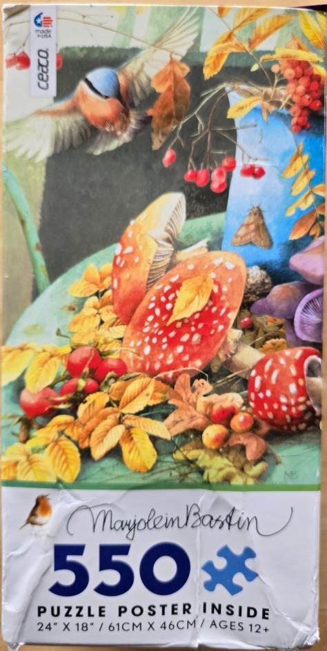 A nuthatch flying toward a blue vase surrounded by autumn leaves, red berries, and fly agaric mushrooms.