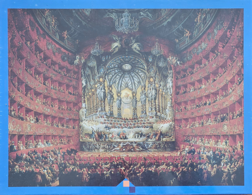 An ornate historical opera house interior featuring tiered red balconies, a grand central stage, and a seated audience.