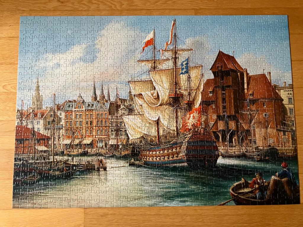 A detailed painting of a historic sailing ship docked in a busy harbor lined with traditional European buildings.