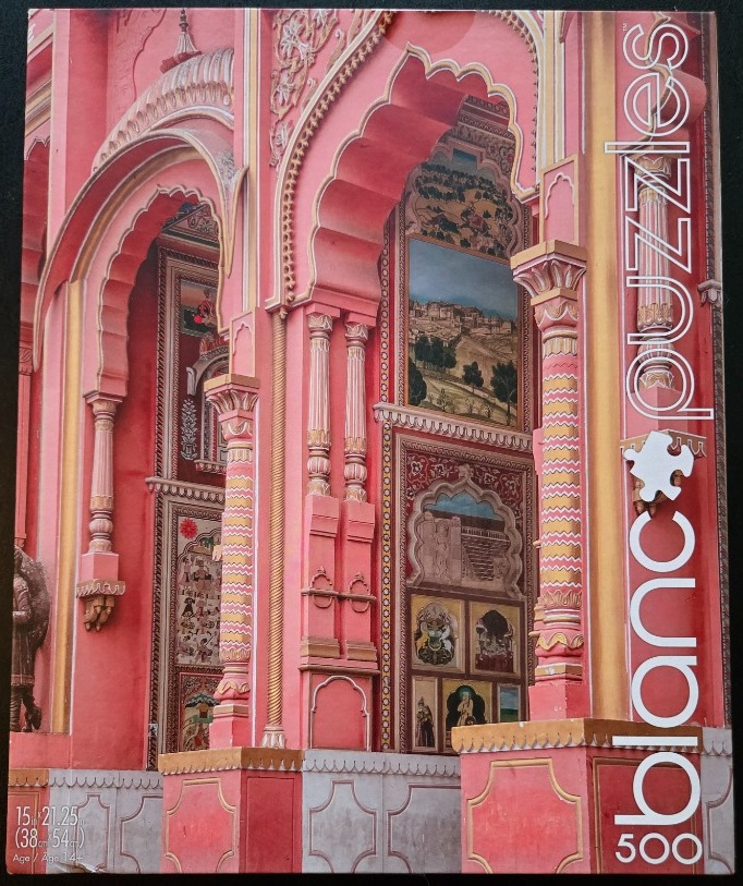 A close-up view of an ornate, salmon-pink Indian palace facade with decorative arches and painted wall murals.