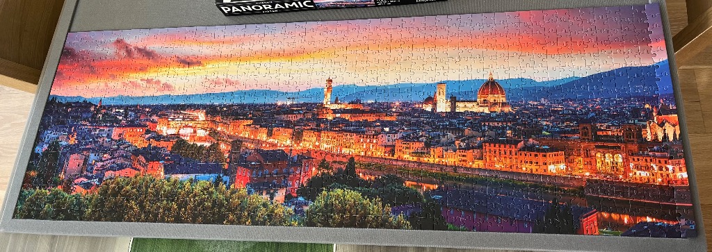 A panoramic photograph of Florence, Italy at sunset with the Duomo illuminated against a vibrant orange sky.