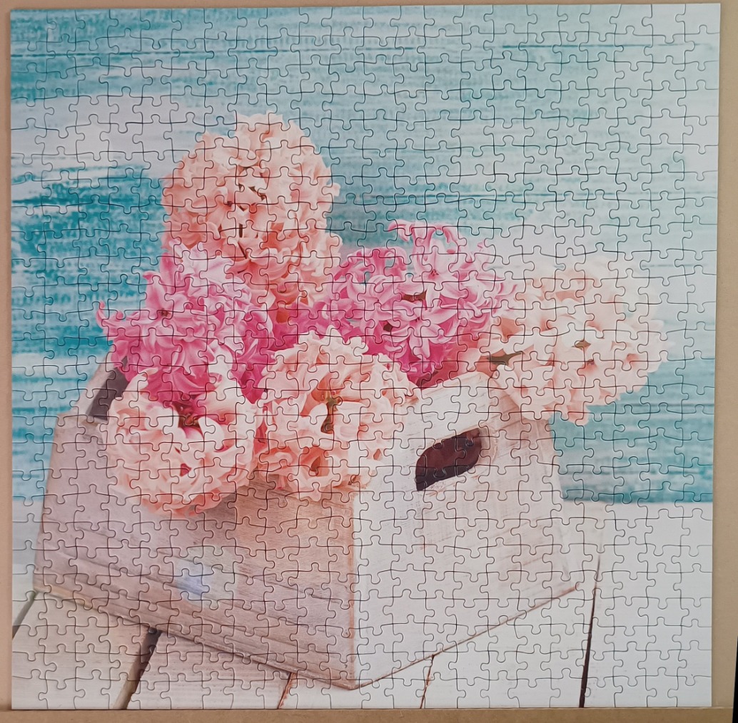 A wooden crate filled with pink hyacinth flowers against a blue distressed wood background.