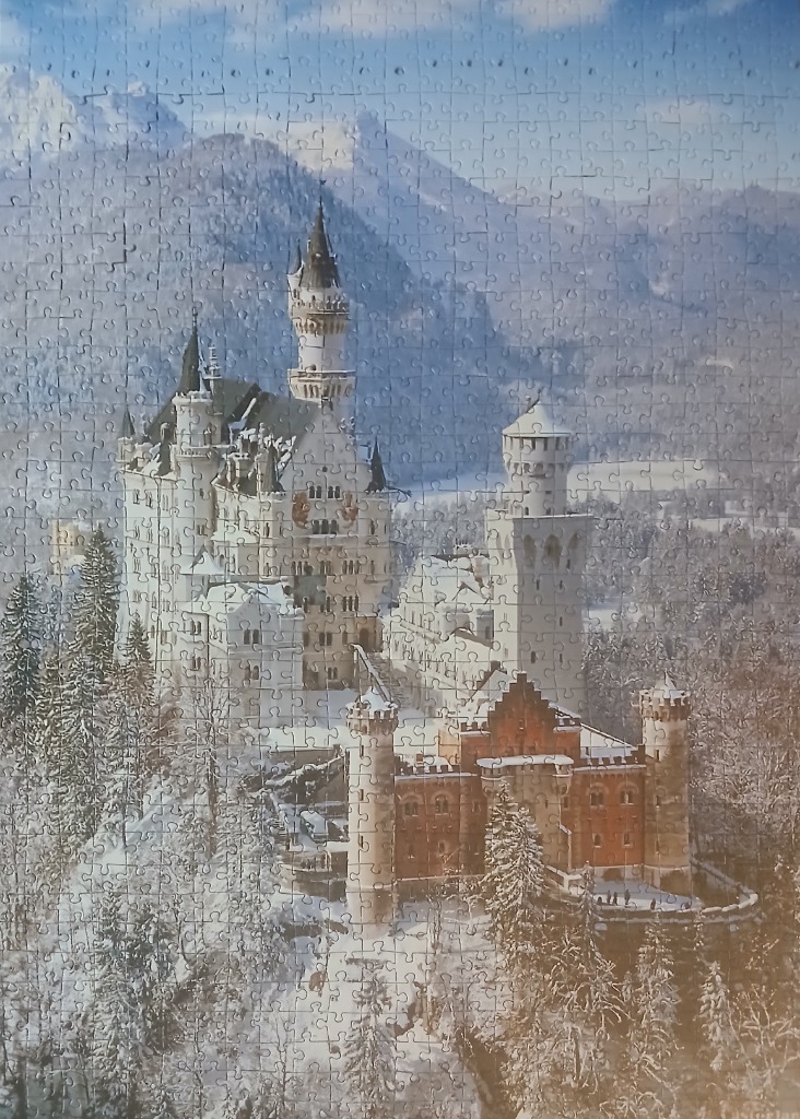 Neuschwanstein Castle surrounded by a snow-covered forest and mountains.