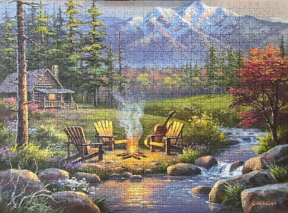 A painting of a cozy campsite with a fire, chairs, and guitar by a stream in front of a mountain range.