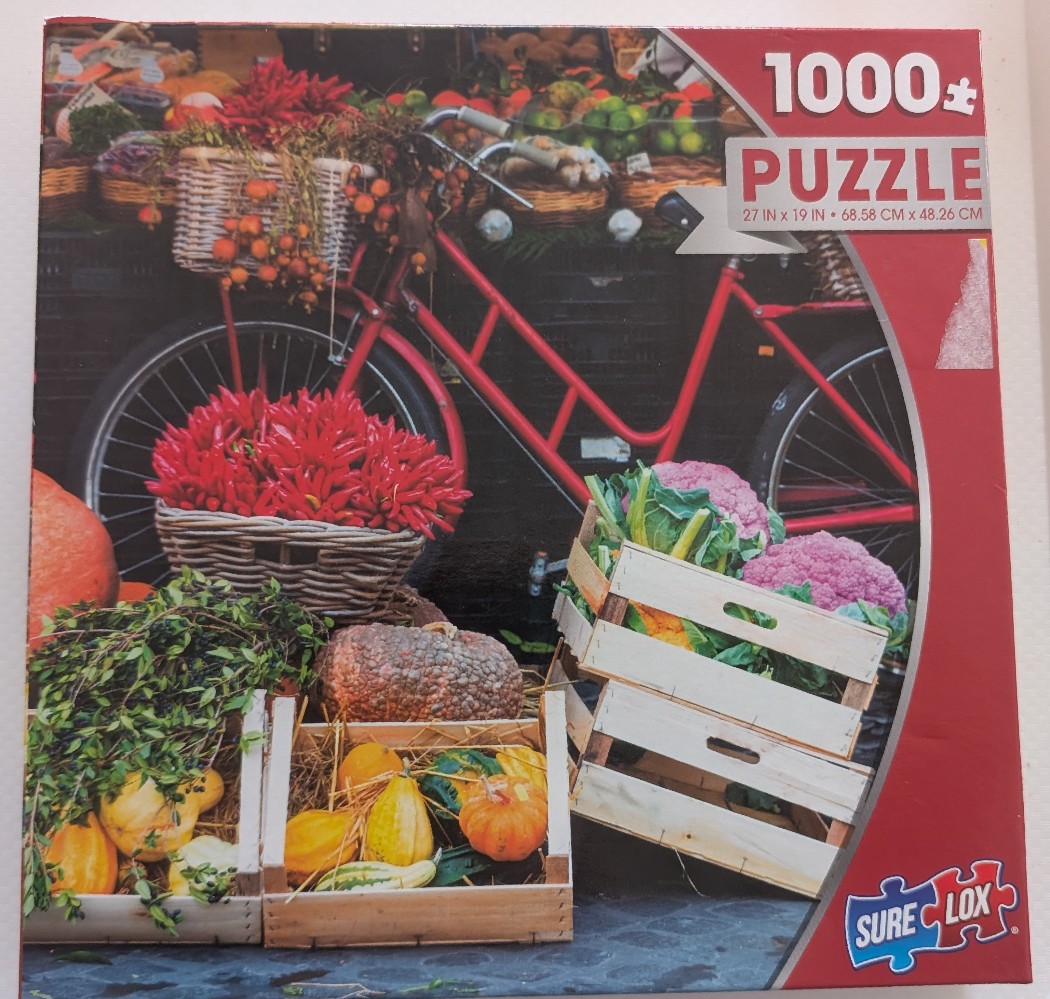 A red bicycle parked behind crates and baskets overflowing with fresh, vibrant vegetables and fruits.