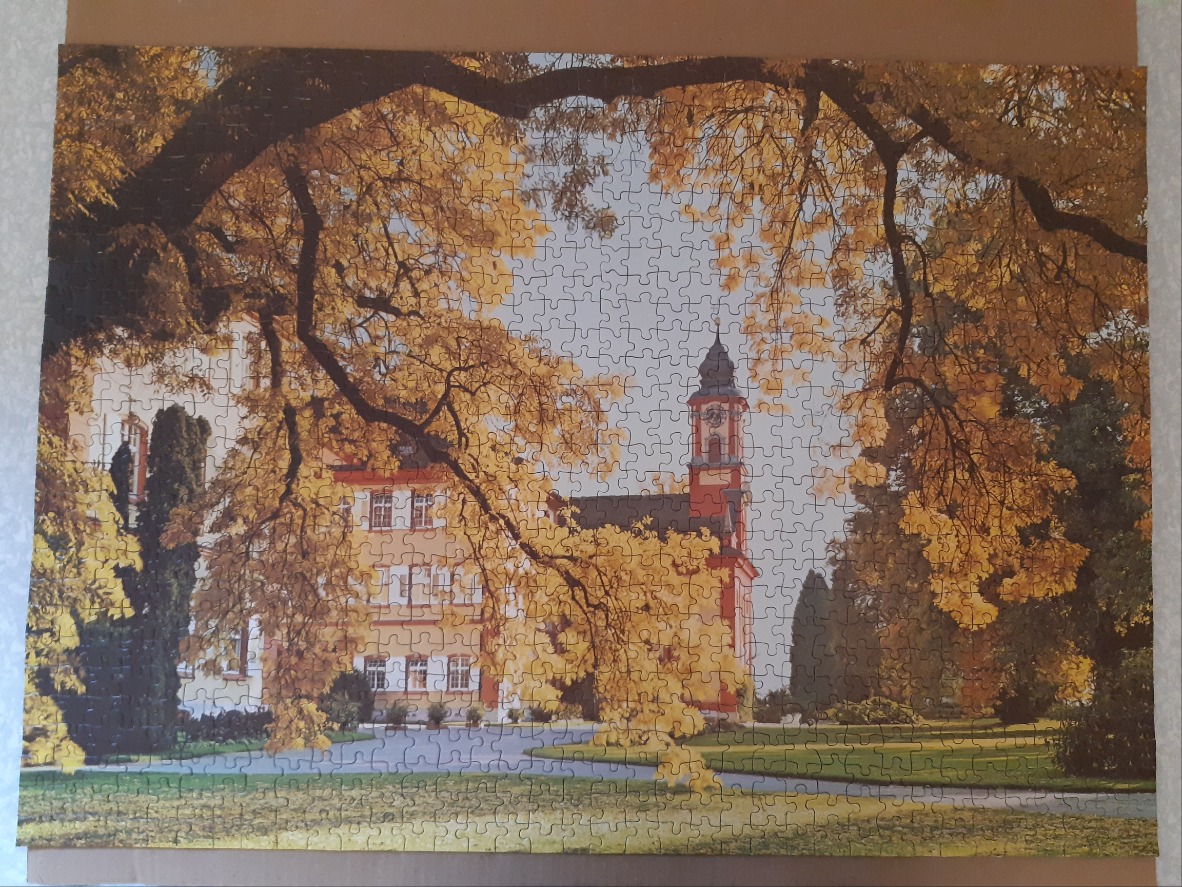 A historic yellow building framed by autumn trees with golden leaves.