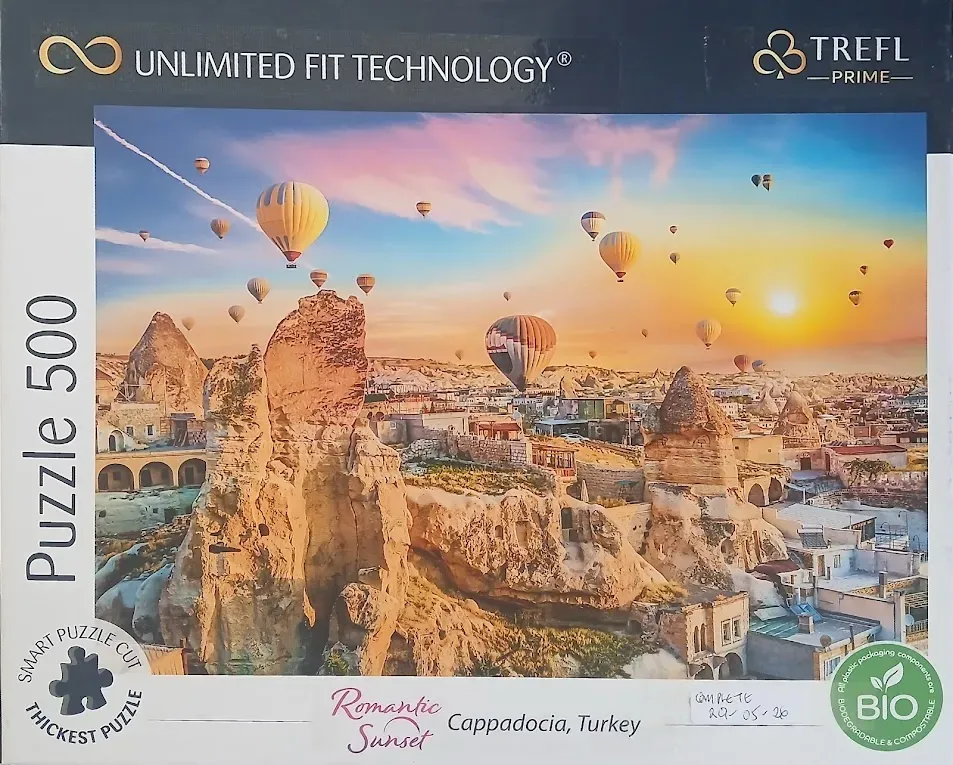 Hot air balloons floating over the rocky landscape of Cappadocia, Turkey at sunset.