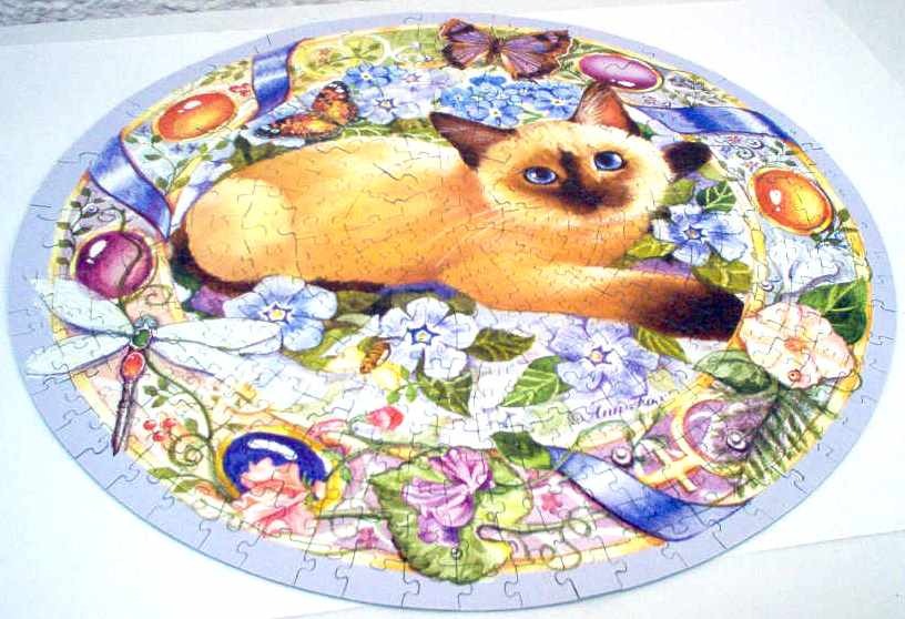 A circular illustration of a Siamese cat resting among colorful flowers, butterflies, and a dragonfly.