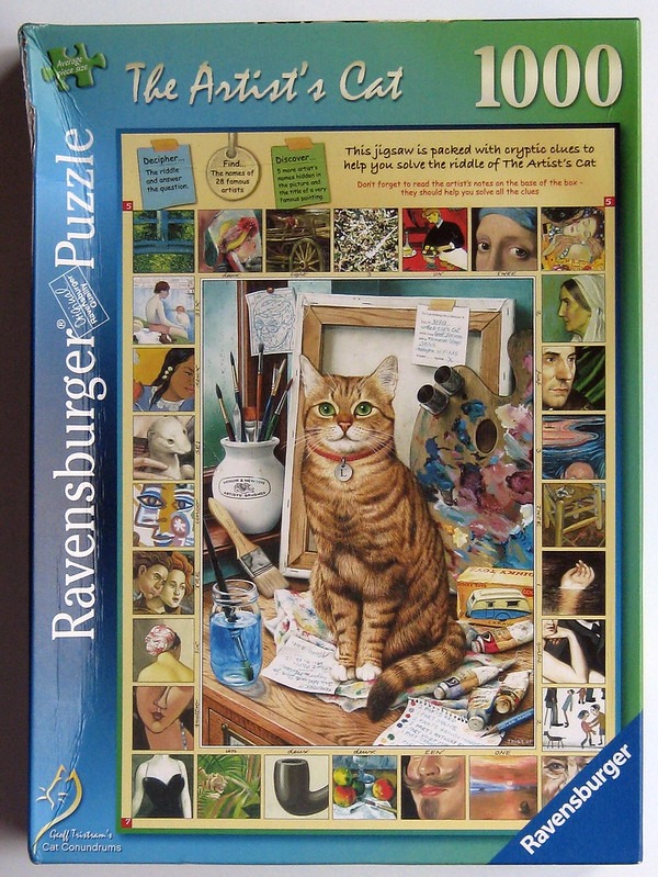 A tabby cat sits on an artist