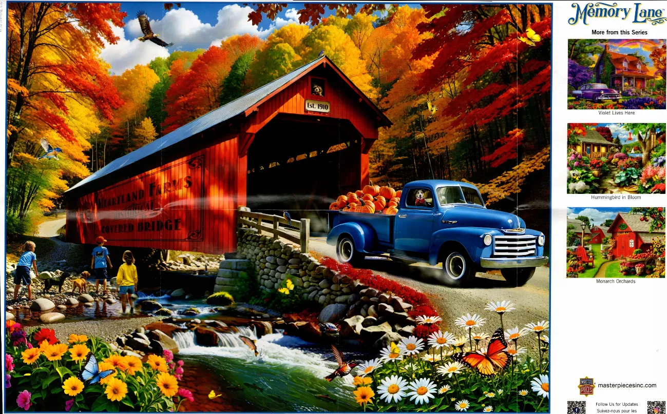 A blue vintage truck loaded with pumpkins crosses a red covered bridge surrounded by vibrant autumn trees.