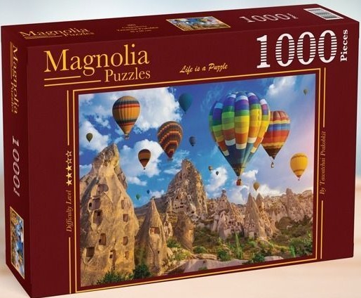 Hot air balloons floating over the fairy chimneys and rock formations of Cappadocia under a blue sky.